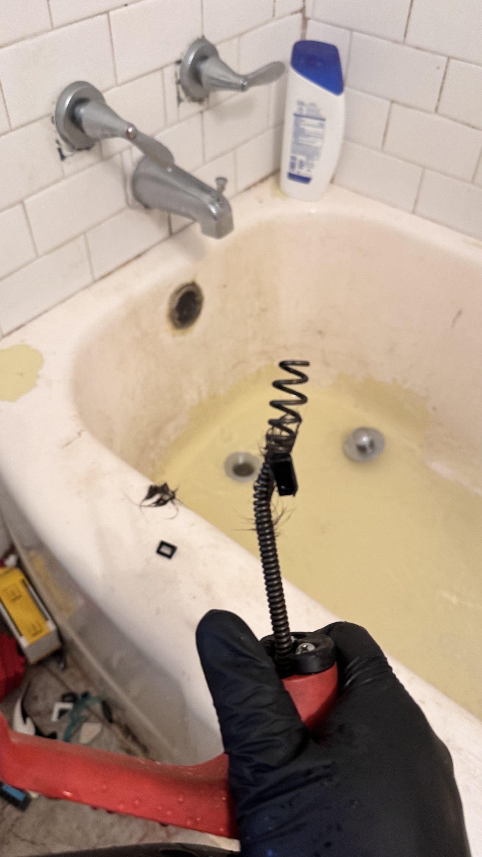 Plumber snaking a clogged bathtub drain during drain cleaning service in Alexandria, VA